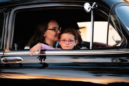Kind und Frau schauen aus einem schwarzen Auto
